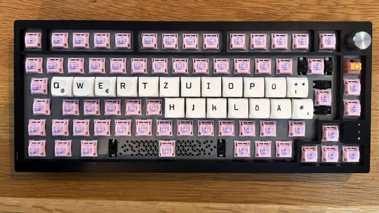 Die besten Switches für Vielschreiber: Deine Finger werden es dir danken Edelstahl-Tastatur mit pinken Custom-Keycaps und weißen Tastenkappen in deutscher Layout.